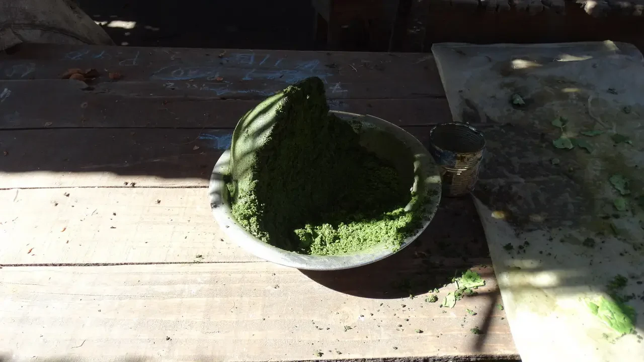 Un mucchio di spezie verdi è disposto su un tavolo all'aperto.