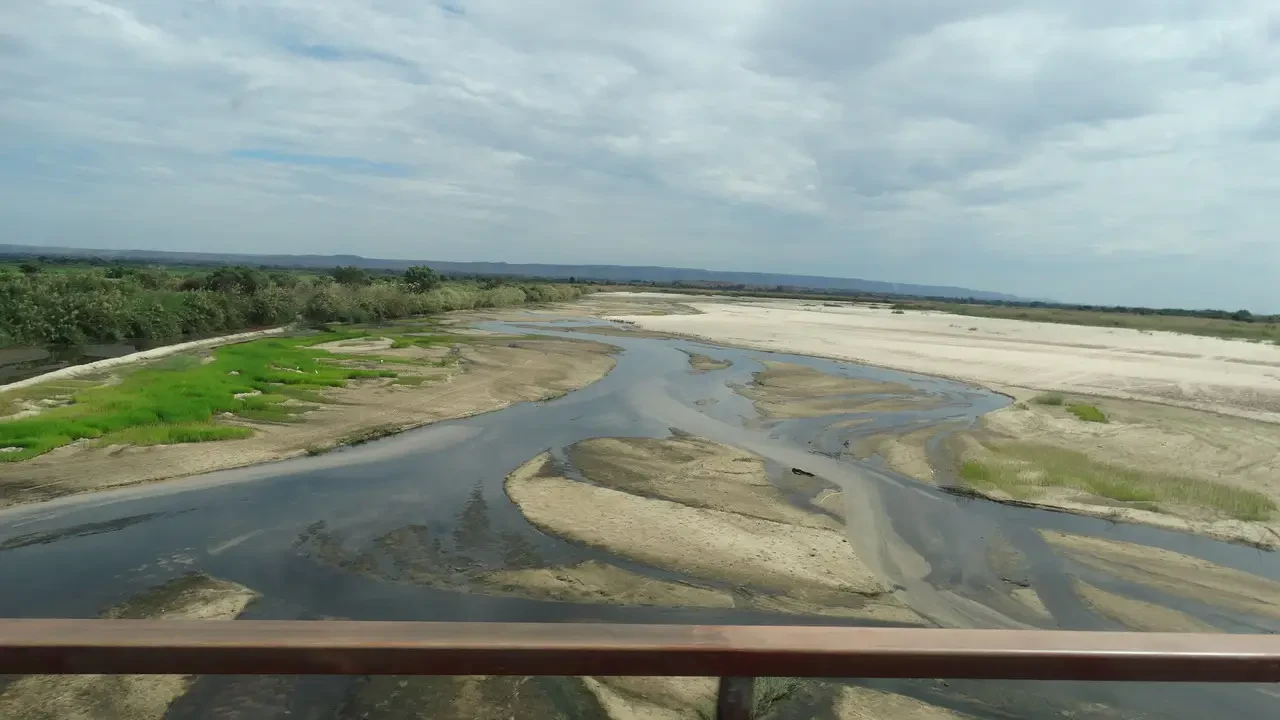 Un fiume poco profondo scorre attraverso un paesaggio secco e fangoso.