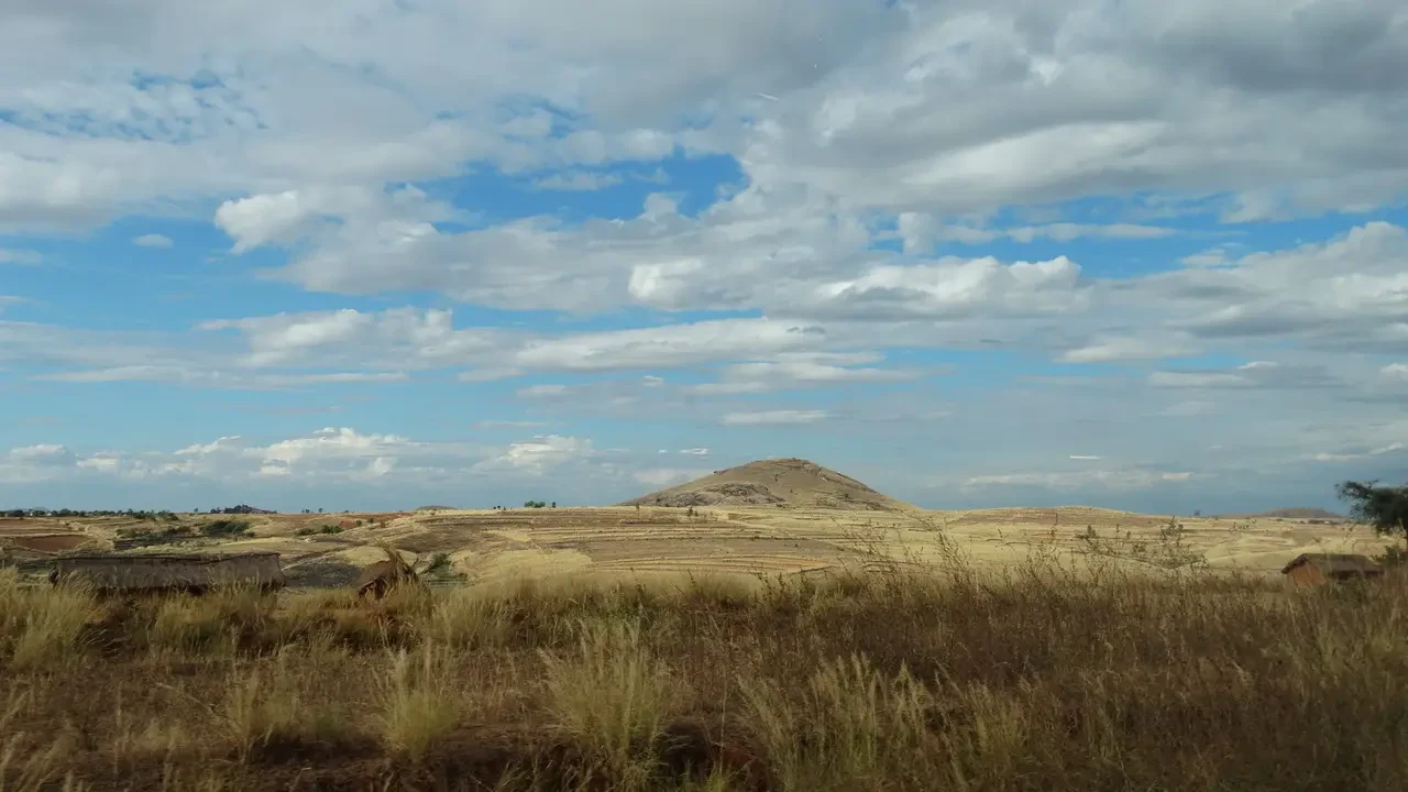 Paesaggio africano con cielo nuvoloso sopra una collina secca.