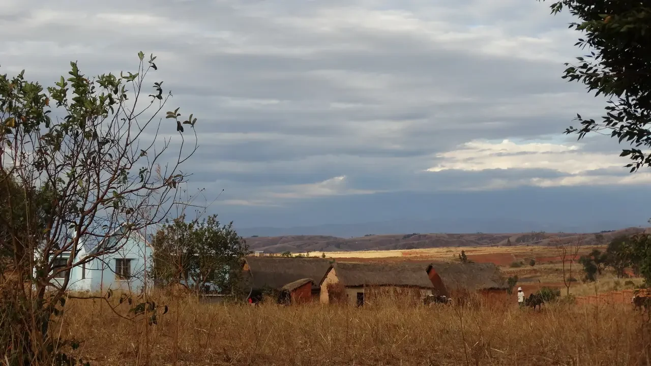 Paesaggio rurale in Madagascara con edifici sotto un cielo nuvoloso.