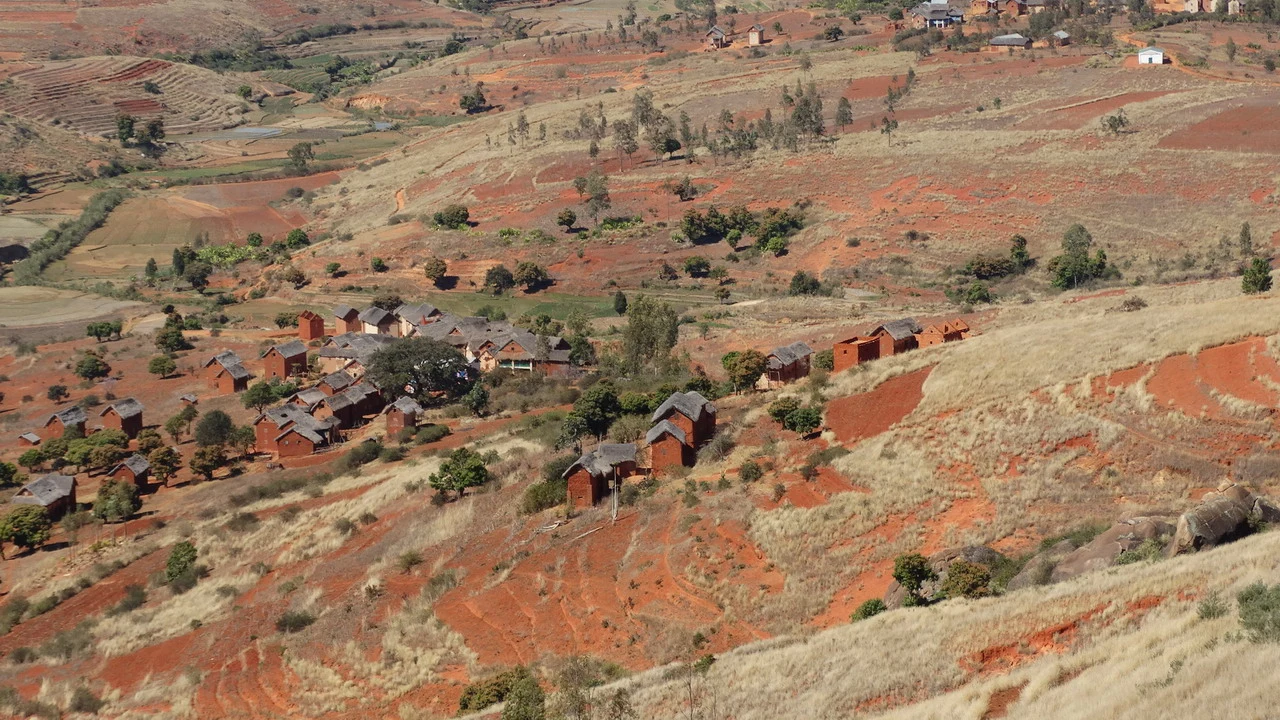 Un paesaggio rurale con abitazioni in terra rossa in Madagascar.