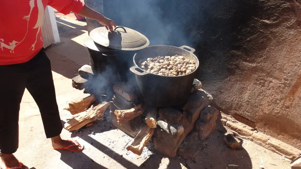 Una persona cucina all'aperto su un fuoco con pentole in Madagascar.