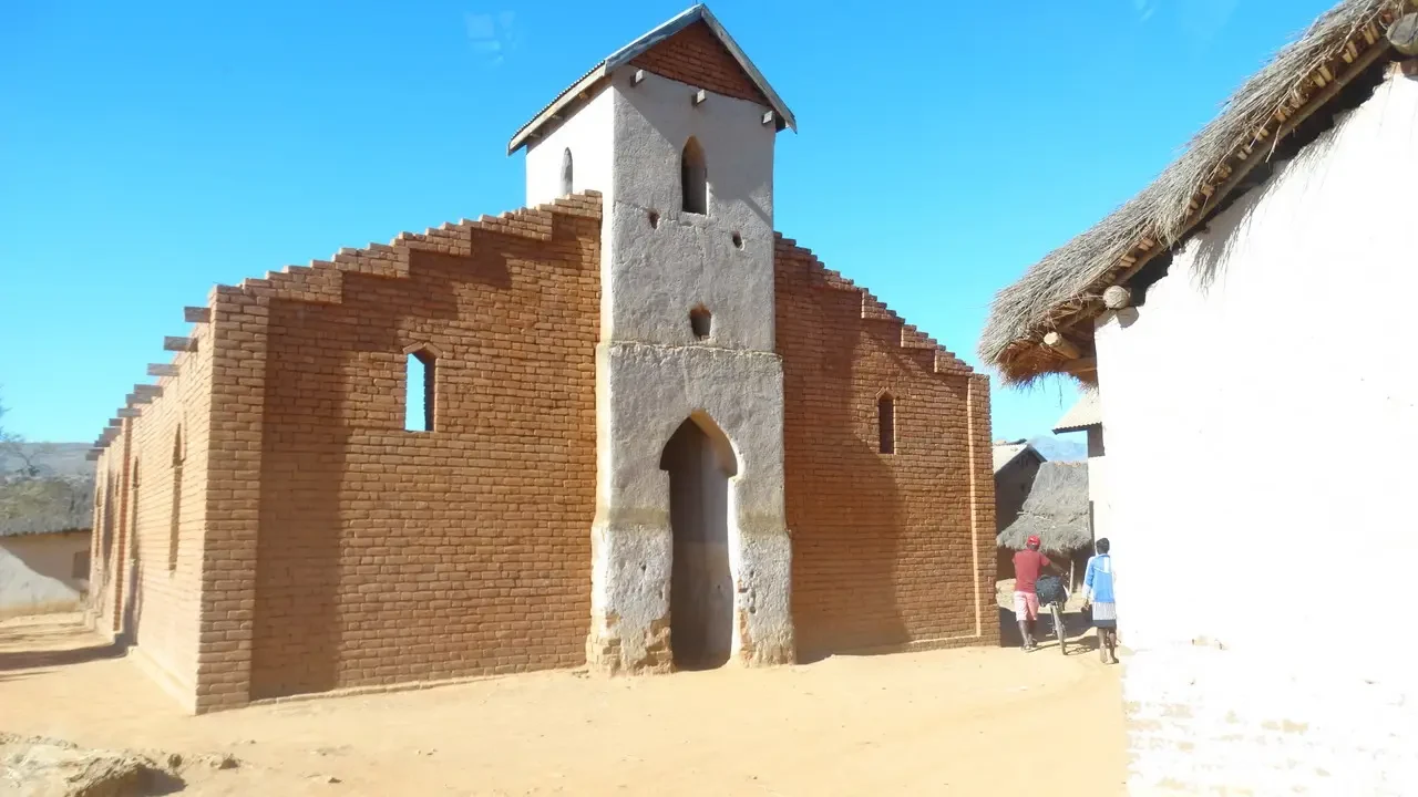 Chiesa in mattoni con tetto a falde visibile sotto il cielo blu.
