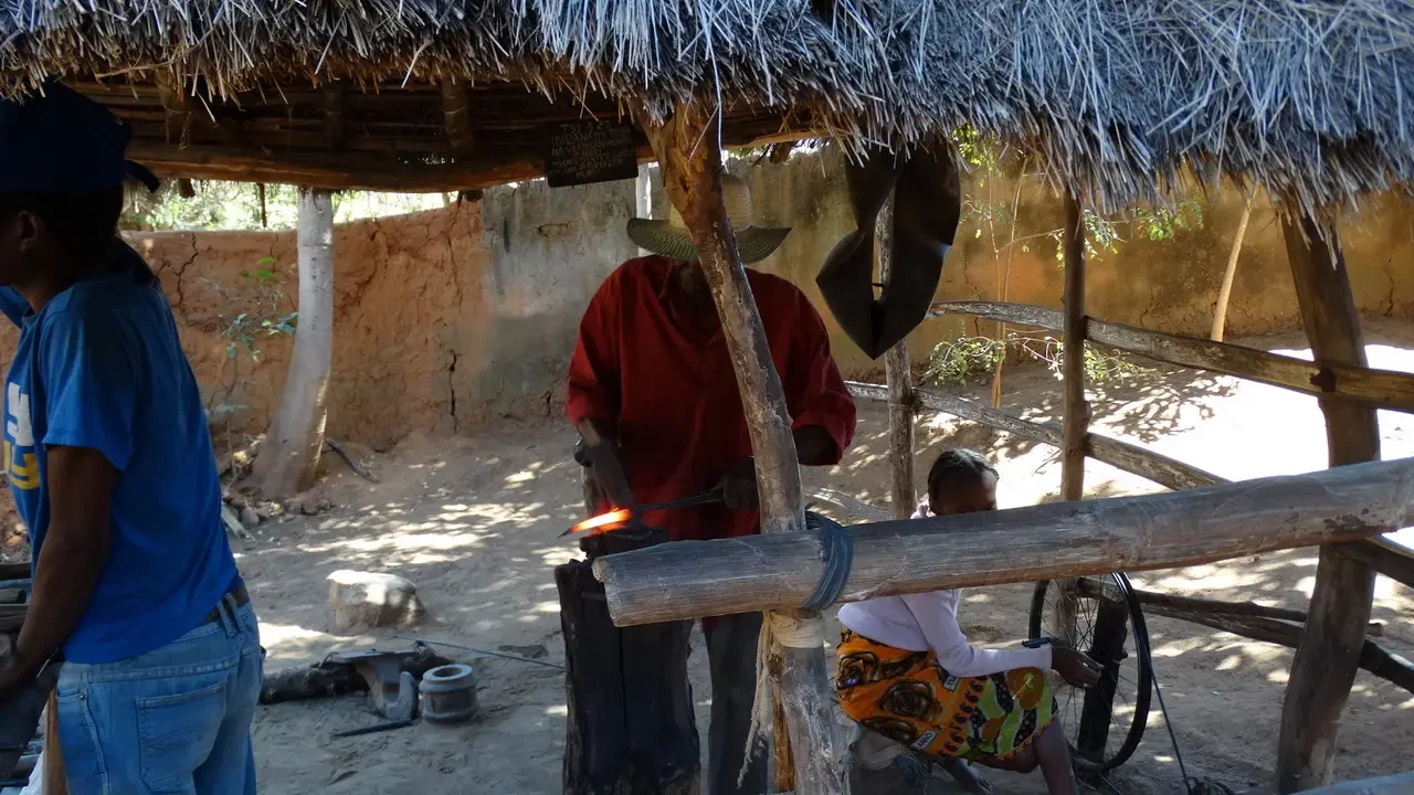 Persone lavorano all'interno di una struttura rustica aperta con tetto di paglia.