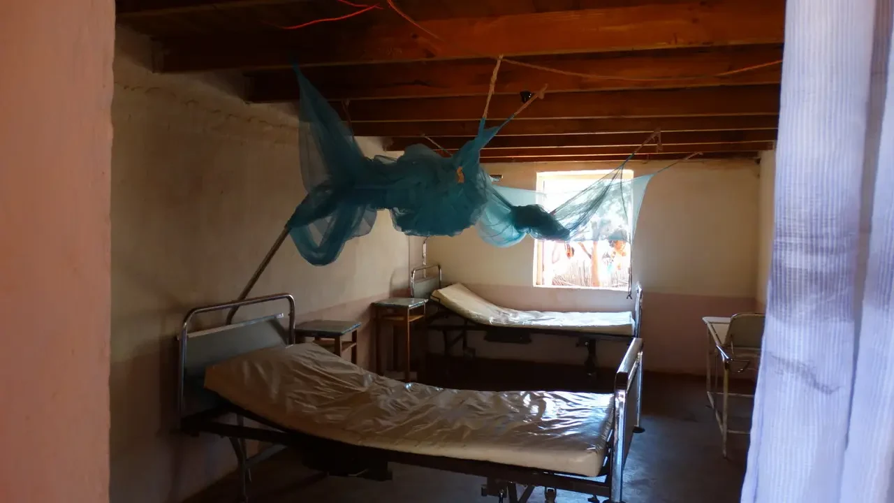 Interno rustico di una stanza con letti e drappeggi in un contesto rurale malgascio.