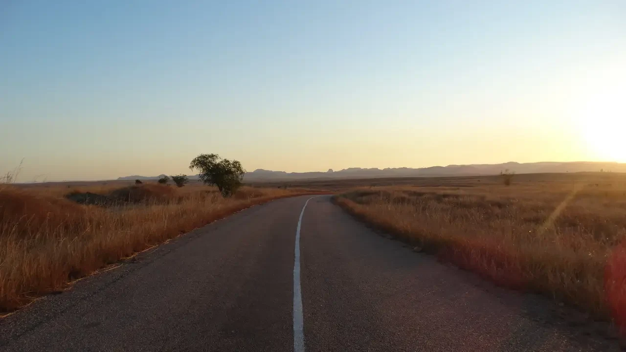 Una strada sterrata attraversa un paesaggio secco all'alba in Madagascar.