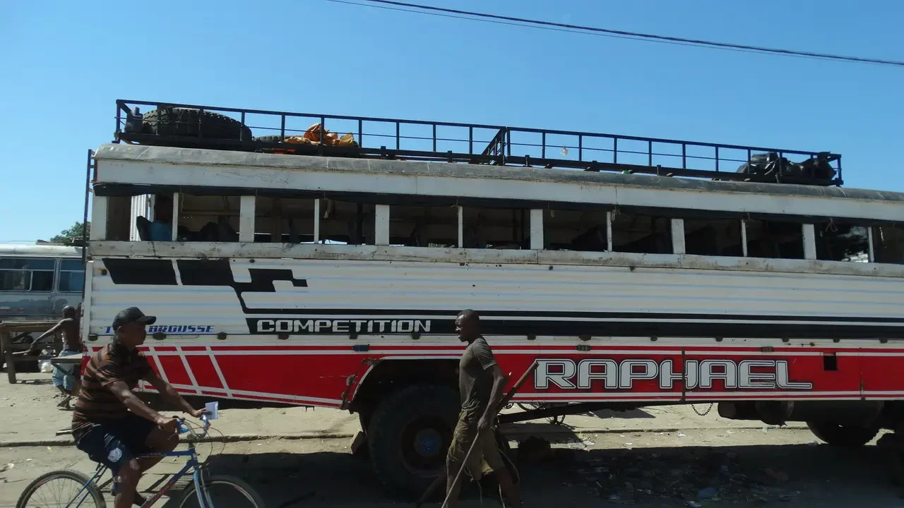 Un autobus rosso con la scritta 'COMPETITION' è parcheggiato in un ambiente esterno.