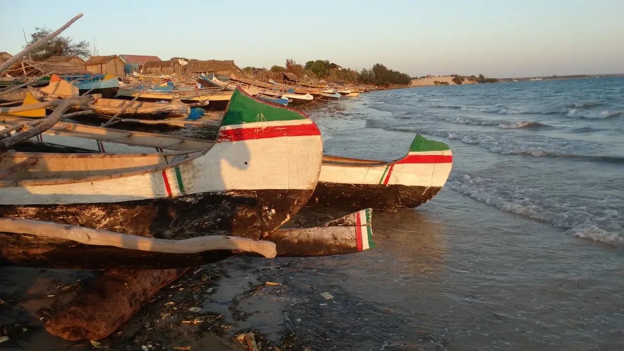 Barche tradizionali decorate sono accostate alla riva durante il tramonto.