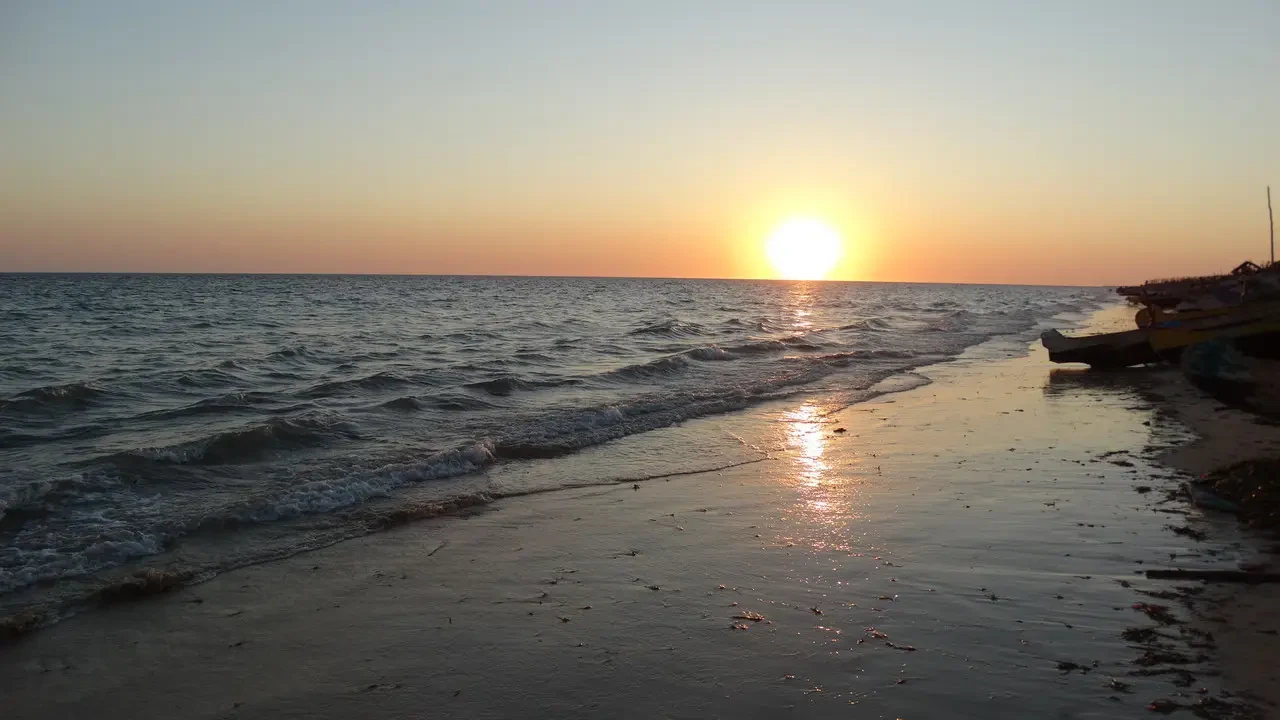 Tramonto del sole dorato sull'oceano con onde che si infrangono sulla spiaggia bagnata.
