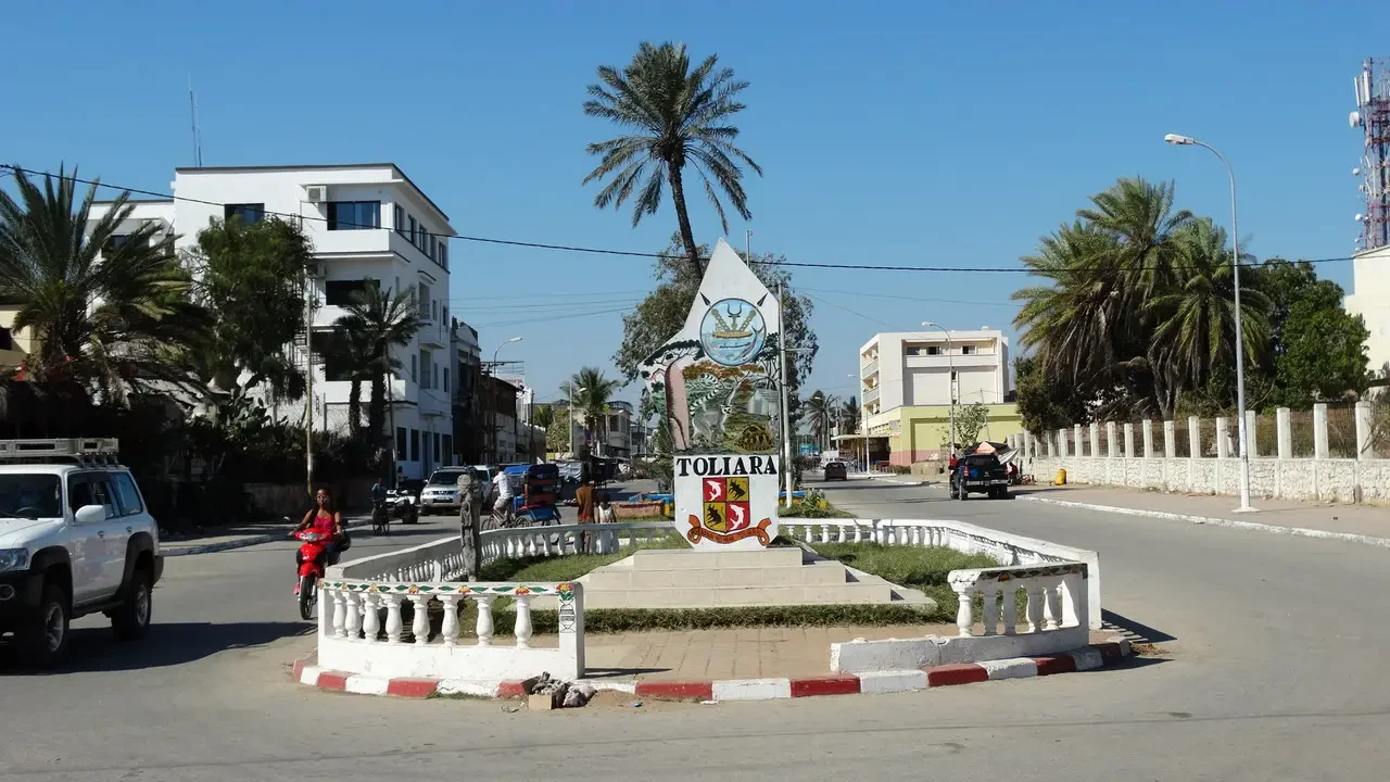 Vista di una piazza con un monumento in stile colonnato e palme in una città malgachesi.