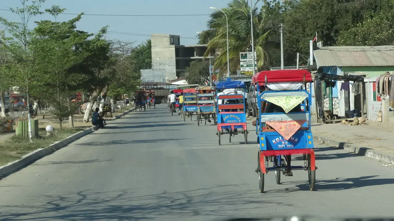 Una strada in una città di Madagascar con veicoli in movimento.