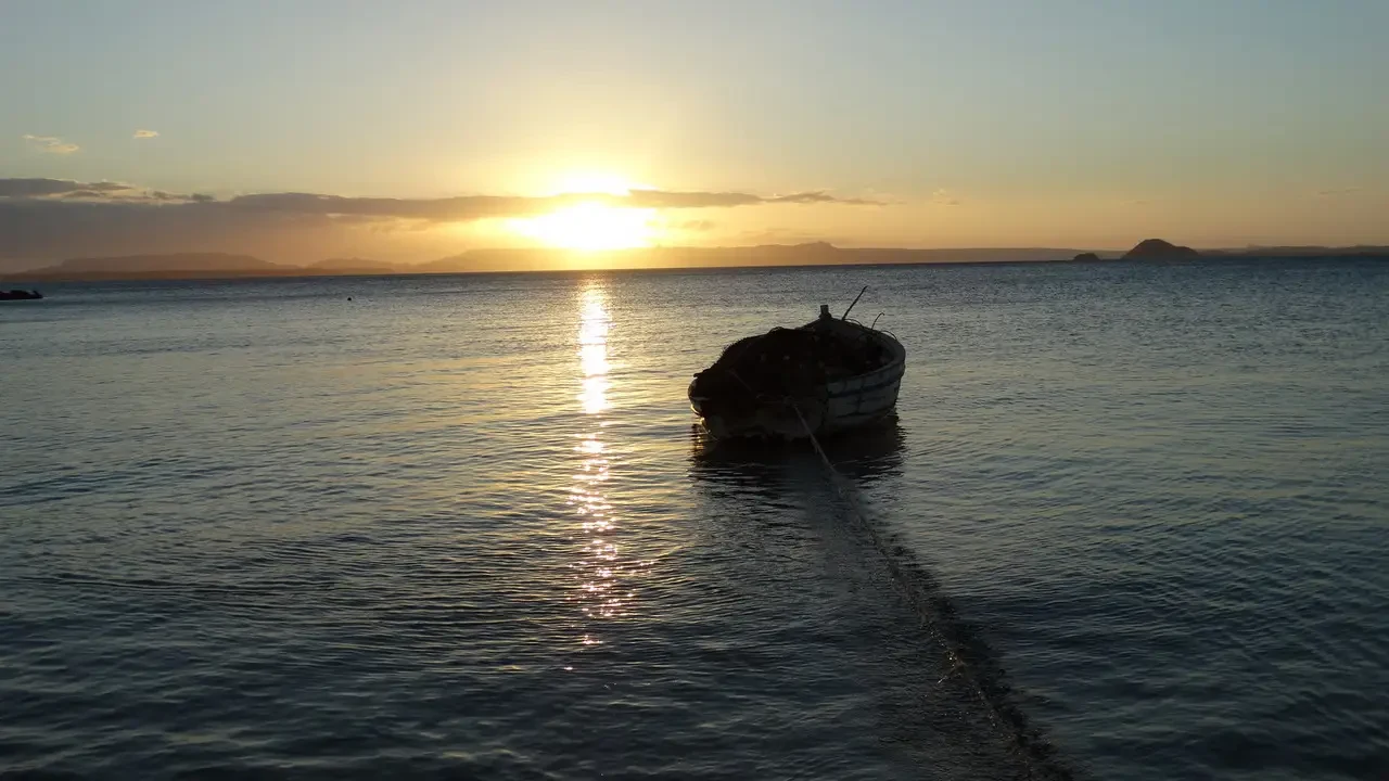 Un piccolo scafo galleggia sull'acqua al tramonto in Madagascar.
