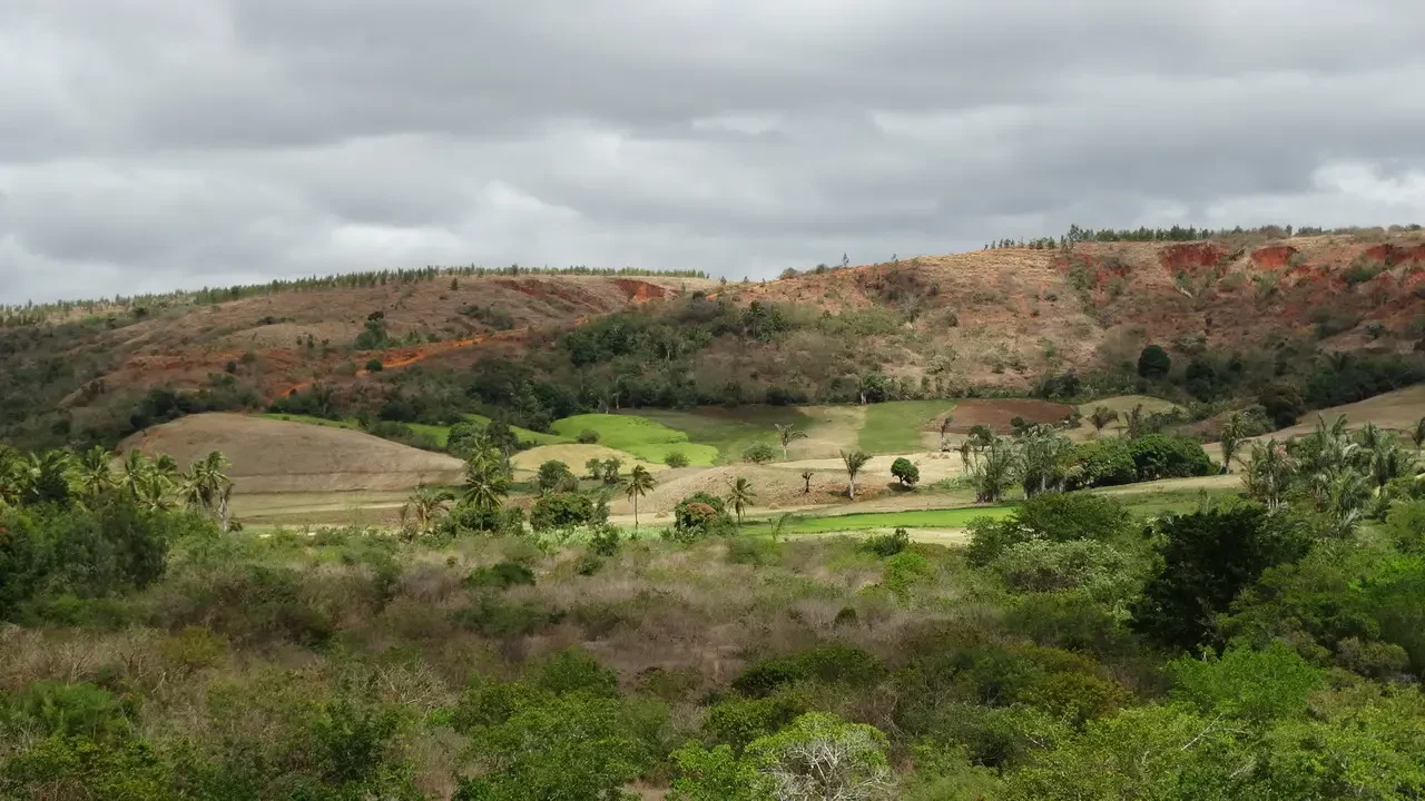 Paesaggio rurale e collinare a Madagascar sotto un cielo nuvoloso.