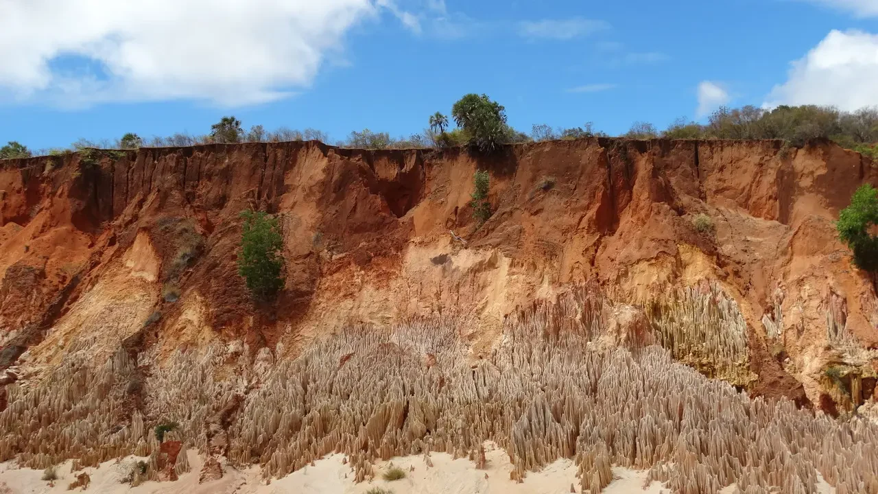 Paesaggio roccioso rosso e arido di Madagascar sotto un cielo azzurro.