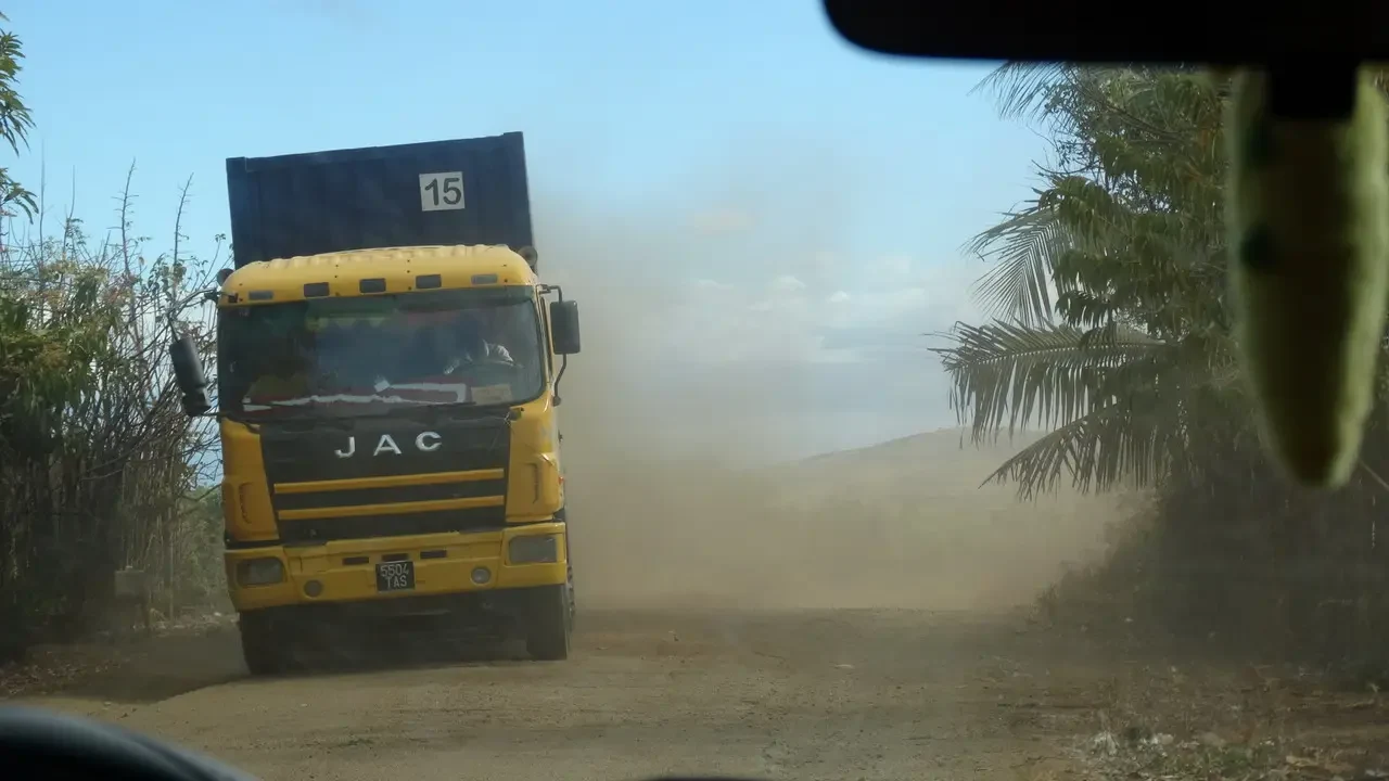Un camion giallo percorre una strada sterrata polverosa in Madagascar.