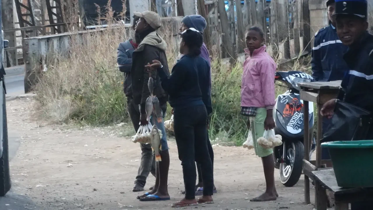 Uomini e bambini sono in piedi su una strada sterrata in un ambiente rurale di Madagascar.