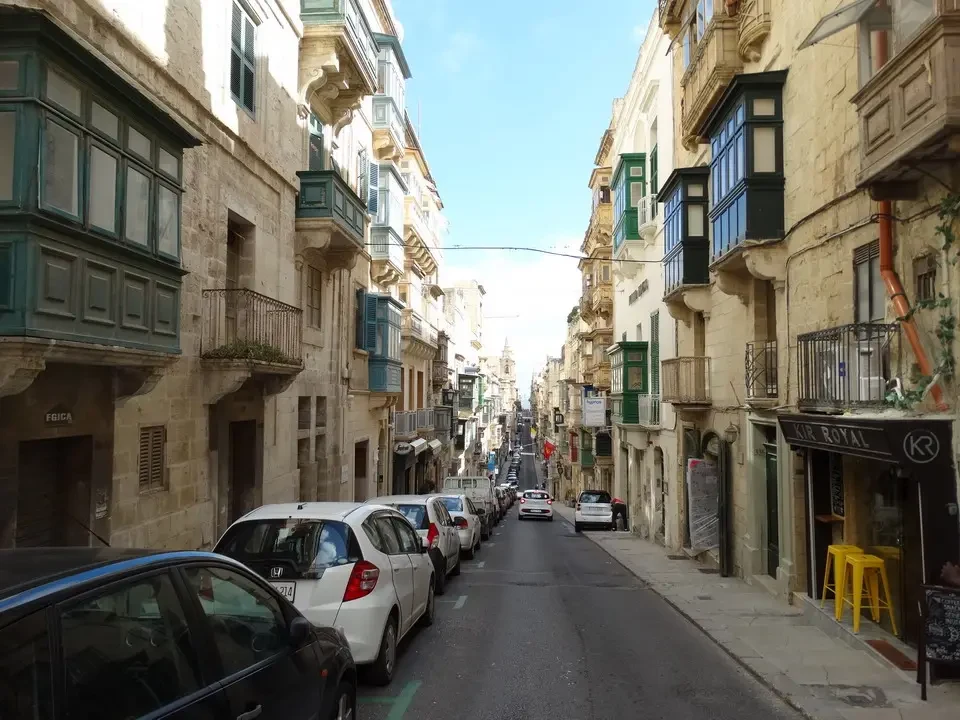 Una strada acciottolata in una città storica di Malta con edifici colorati ai lati.