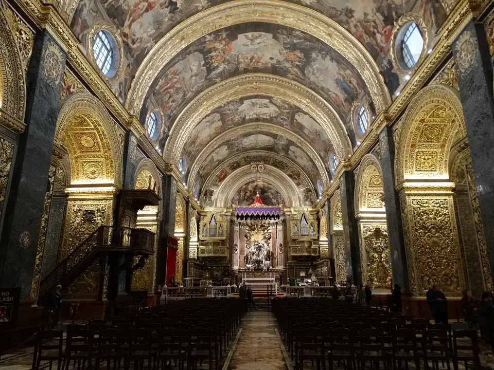 Interno sontuoso della Cattedrale di San Giovanni a Valletta con decorazioni dorate e affreschi.