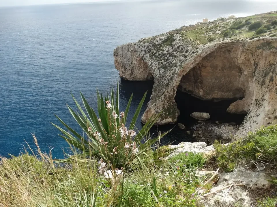 Una grotta rocciosa si affaccia sul mare blu mediterraneo.