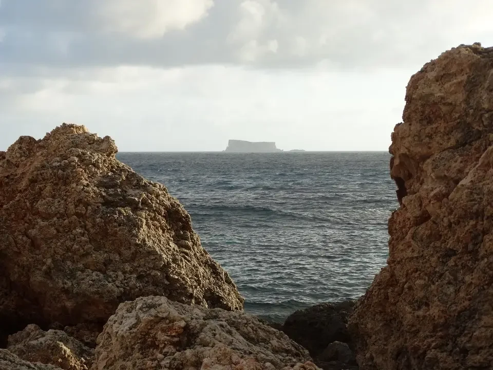Vista del mare con un'isola lontana tra rocce rocciose.