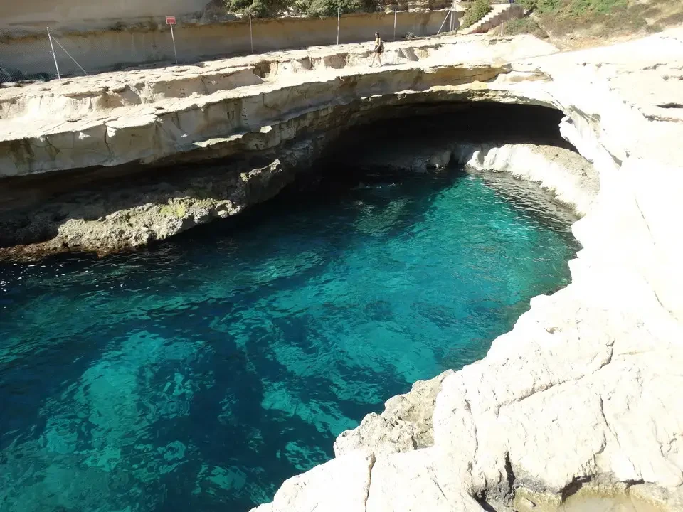 Una vista panoramica di una grotta marina costeggiata da rocce chiare e acqua turchese.