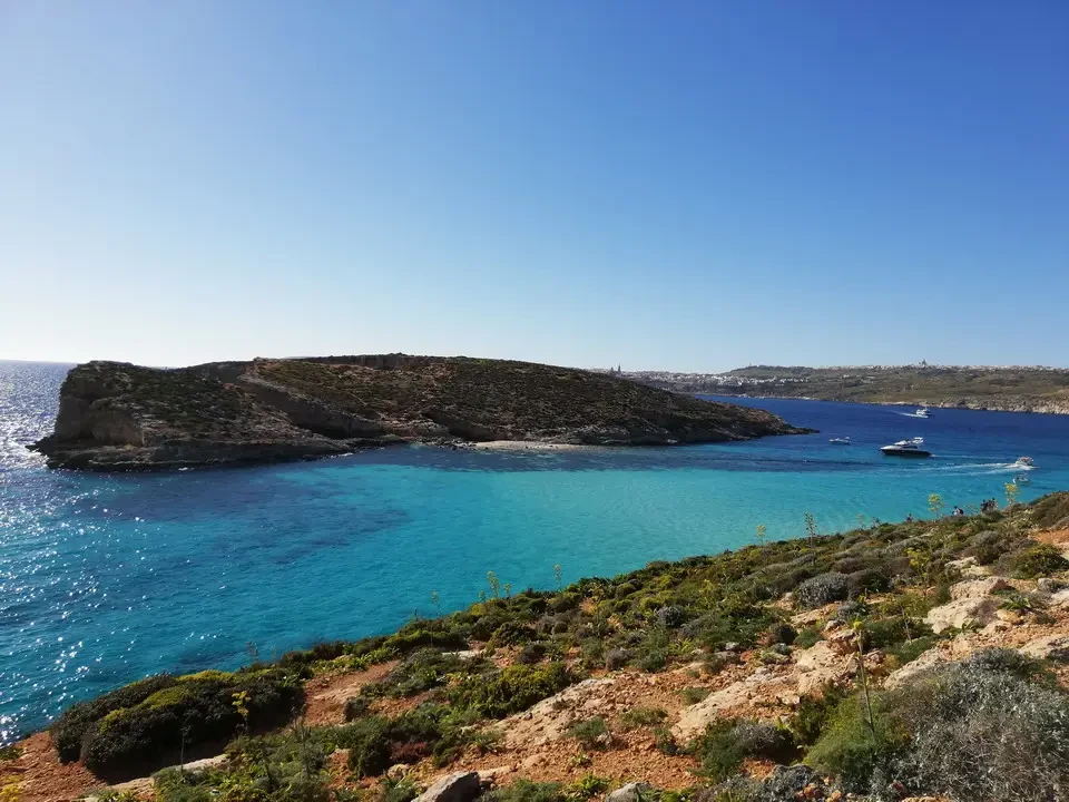 Una laguna blu turchese circonda una penisola rocciosa in Malta.