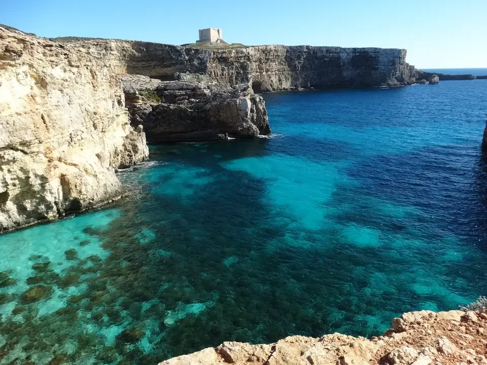 Una veduta panoramica della laguna blu di Comino con un faro in lontananza.