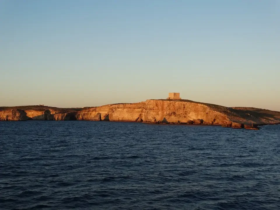 Una costa rocciosa con una piccola struttura in pietra sporge dal mare.