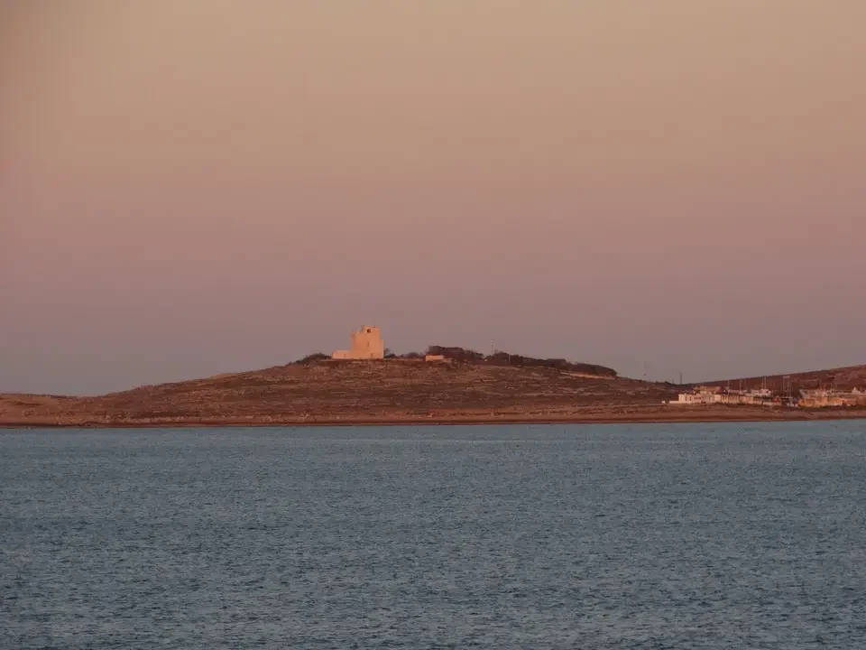 Una struttura in pietra si staglia su una collina sopra l'acqua.