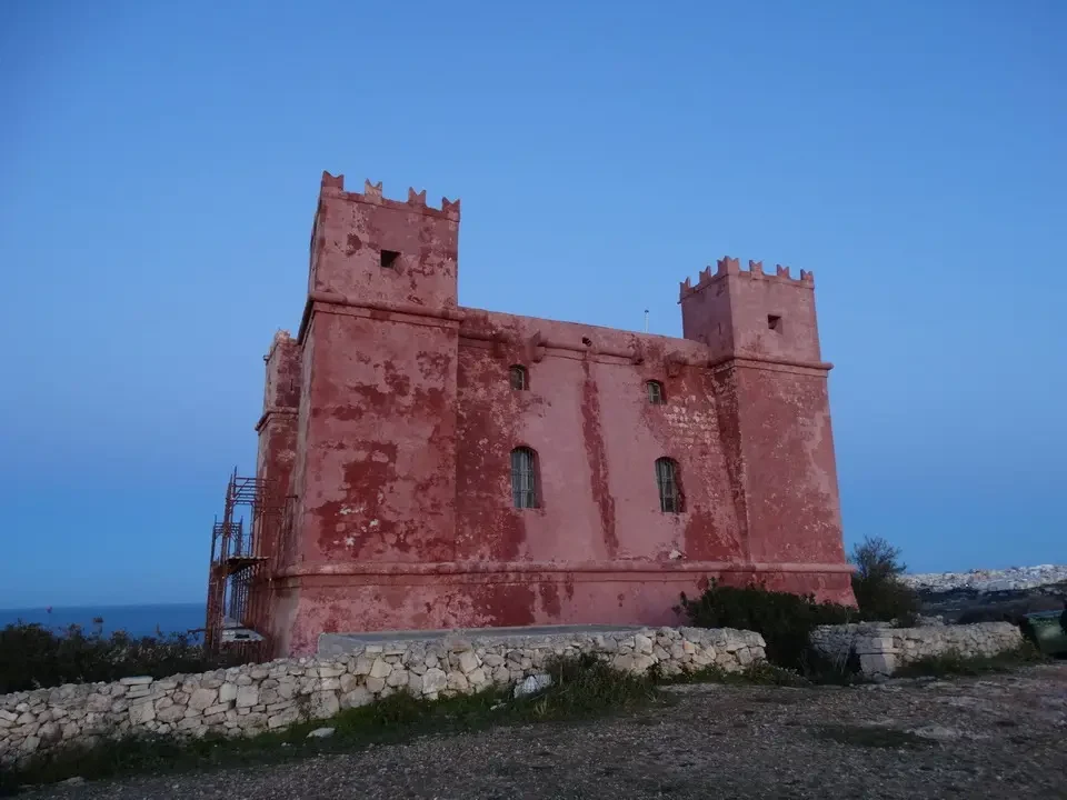 Una torre rossa storica si staglia contro il cielo blu.