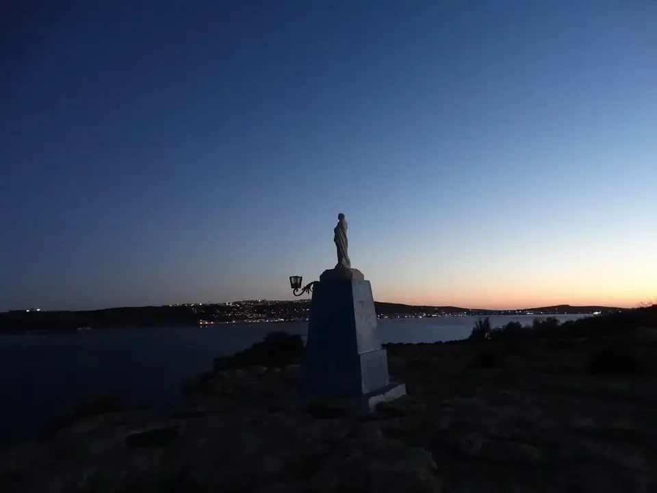Statua di fronte al paesaggio maltaese al tramonto.