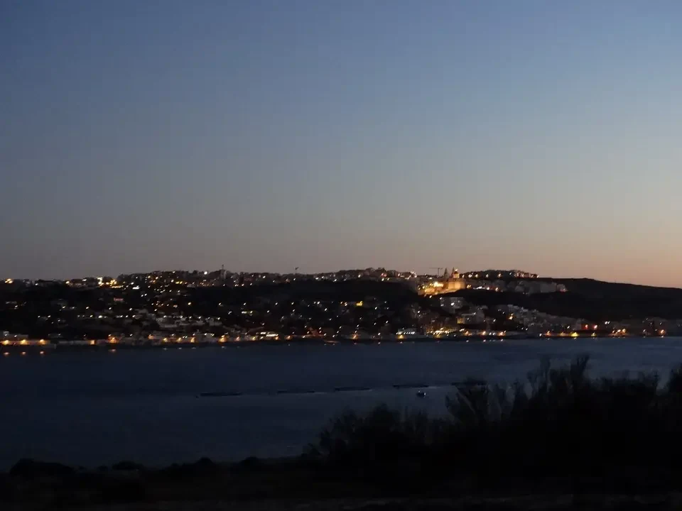 La città è illuminata sulla riva dell'acqua al crepuscolo.