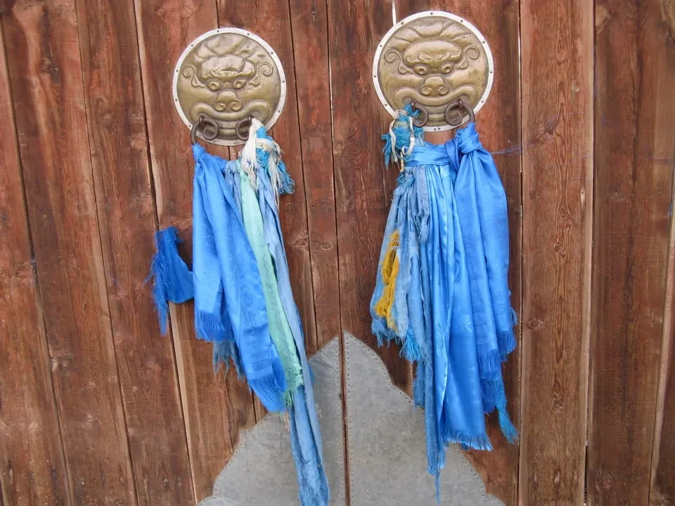 Ingresso di un monastero con porte decorative e drappeggi blu in Mongolia.