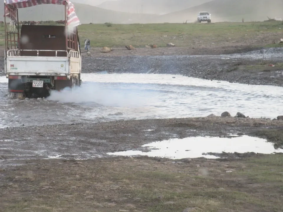 Un camion attraversa un fiume fangoso in una vasta pianura mongola.