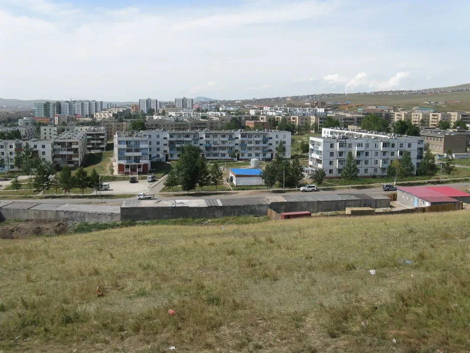 Vista panoramica di un insediamento urbano in Mongolia con edifici residenziali e terreno aperto.