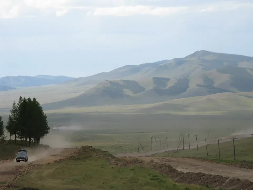 Un veicolo attraversa un paesaggio ondulato e aperto in Mongolia.