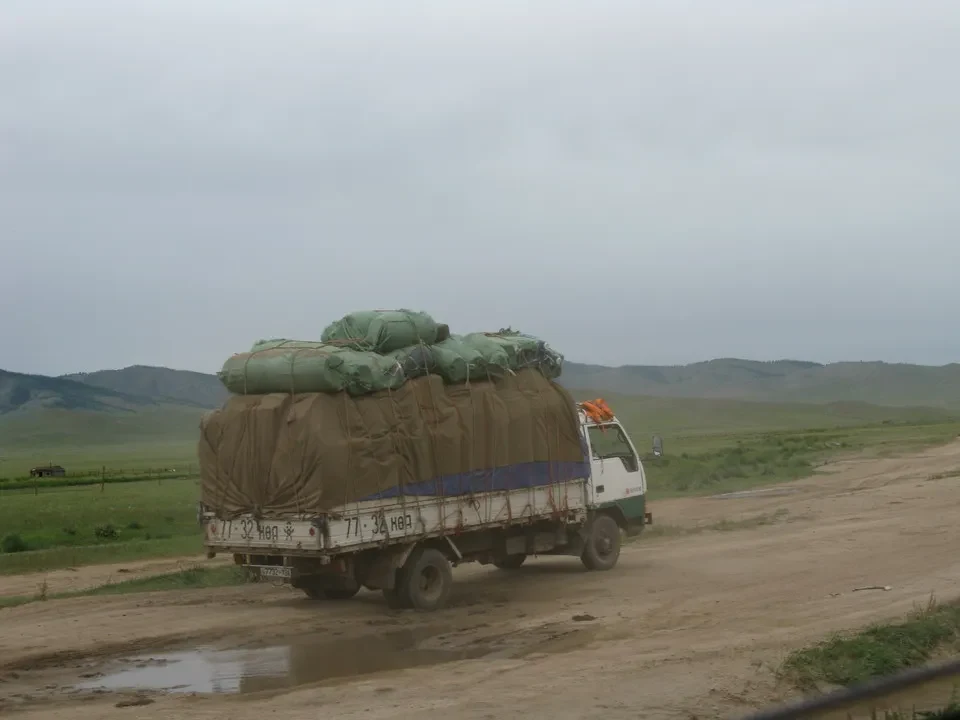 Un camion trasporta balle di fieno su una strada sterrata in Mongolia.