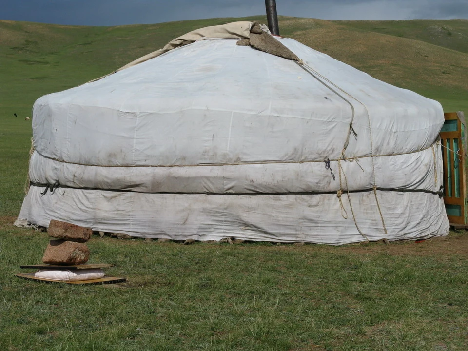 Una tenda tradizionale coperta di tela bianca si trova su un prato in Mongolia.