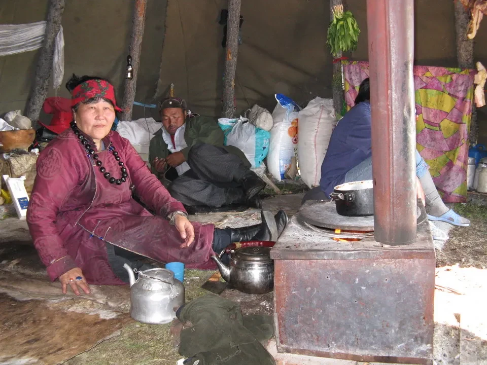 Uomini con renne e sciame in una tenda in Mongolia.