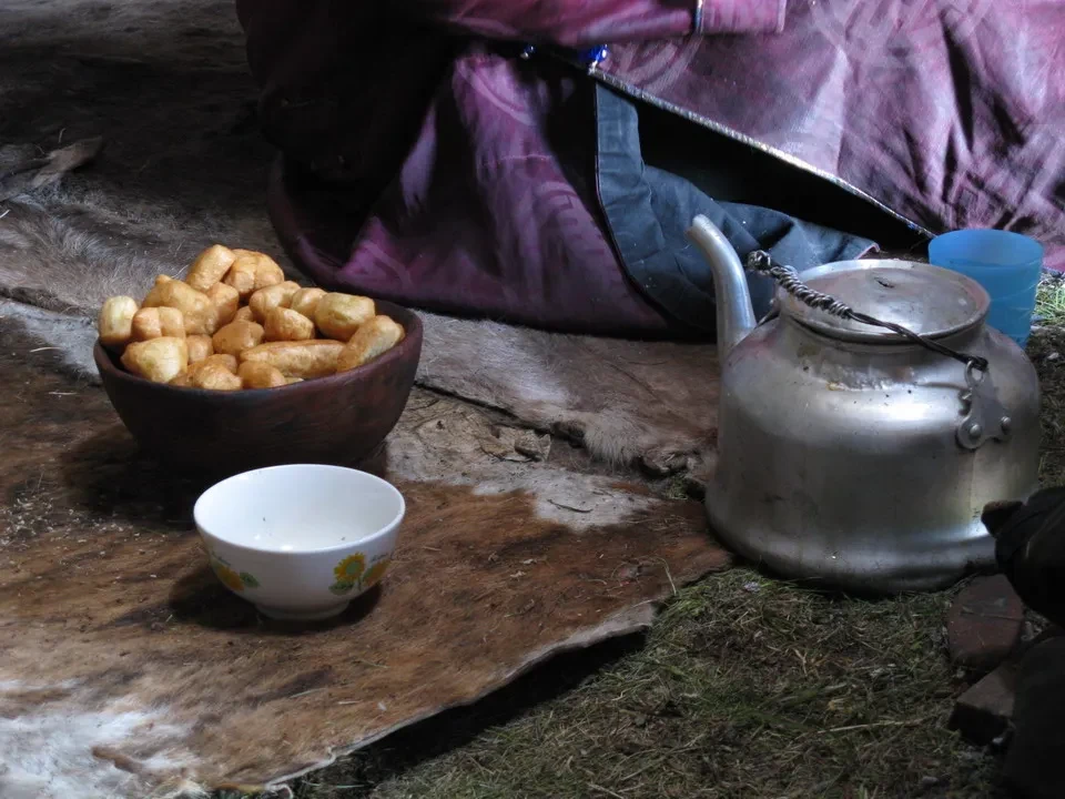 Uomini e ospiti condividono cibo sotto una tenda in Mongolia.
