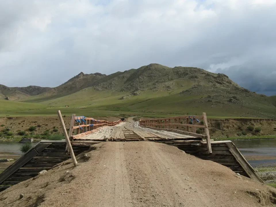 Un ponte di legno attraversa un fiume in una valle mongola.