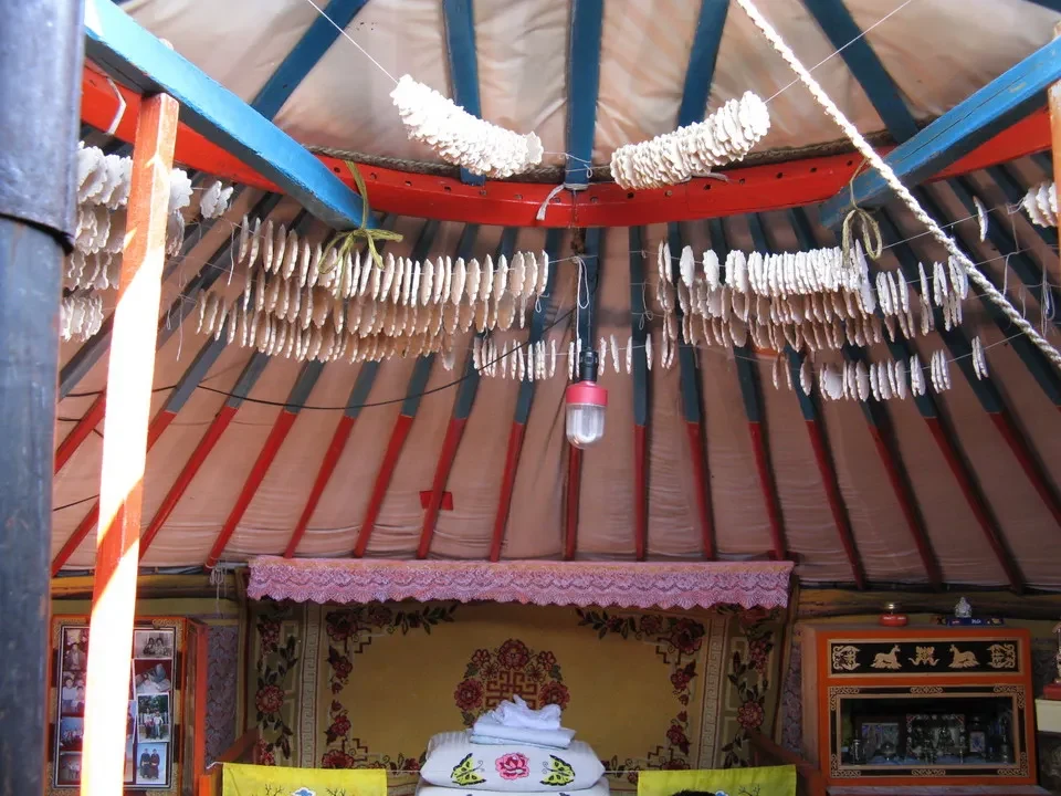 Interni di una tenda tradizionale mongola decorata con frange bianche.