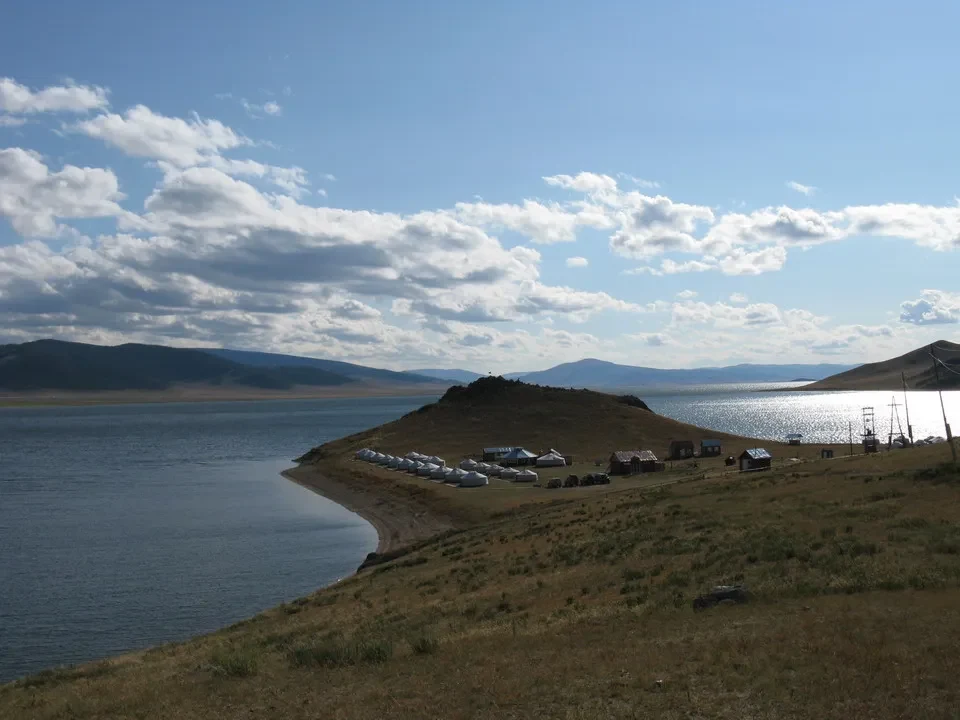 Un campo di tende si estende lungo la riva di un lago in Mongolia.