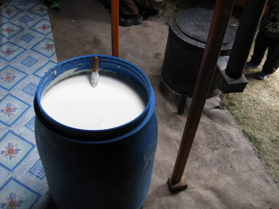 Latte fermentato in un grande barile blu su una struttura rustica.