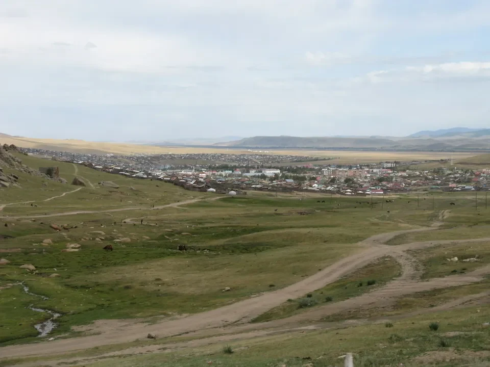 Paesaggio rurale della Mongolia con un insediamento in lontananza.