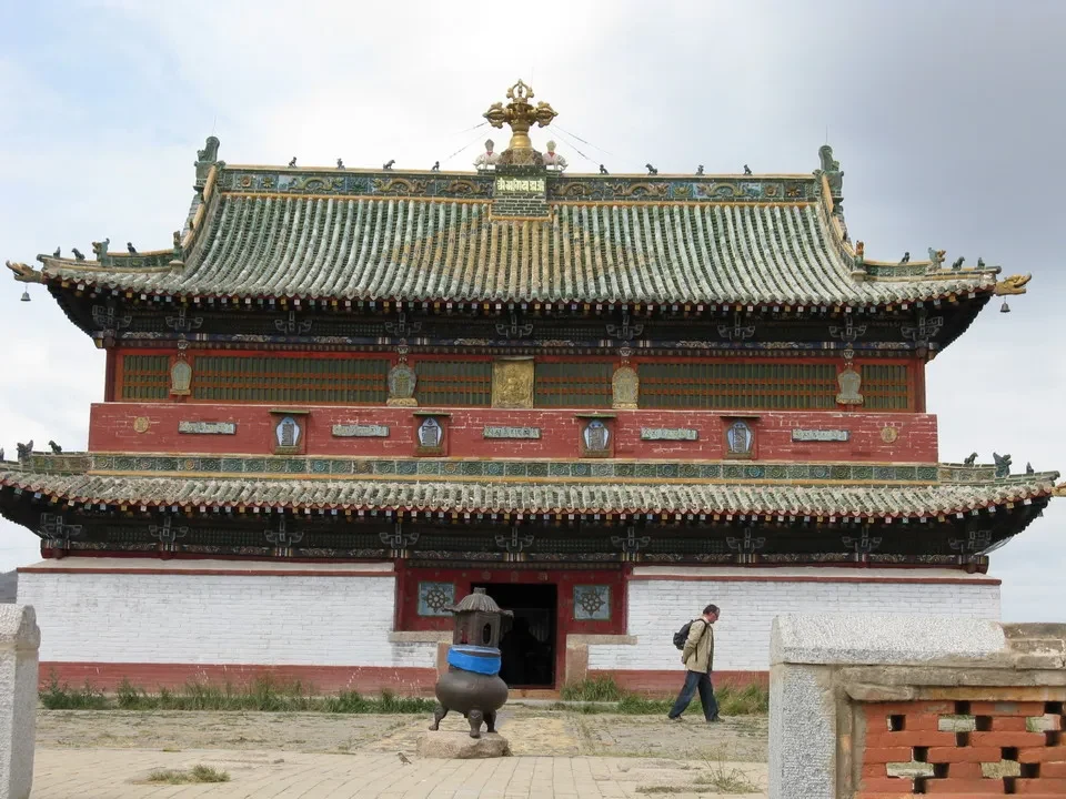Un edificio tradizionale mongolo con tetti curvi e decorati si trova in un paesaggio aperto.