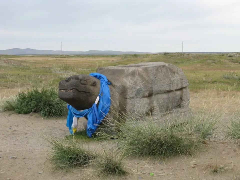Una grande pietra coperta da un drappo blu giace nel paesaggio mongolo.