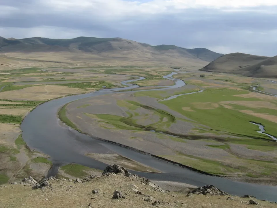 Fiume che serpeggia attraverso una vasta pianura mongola con colline ondulate.