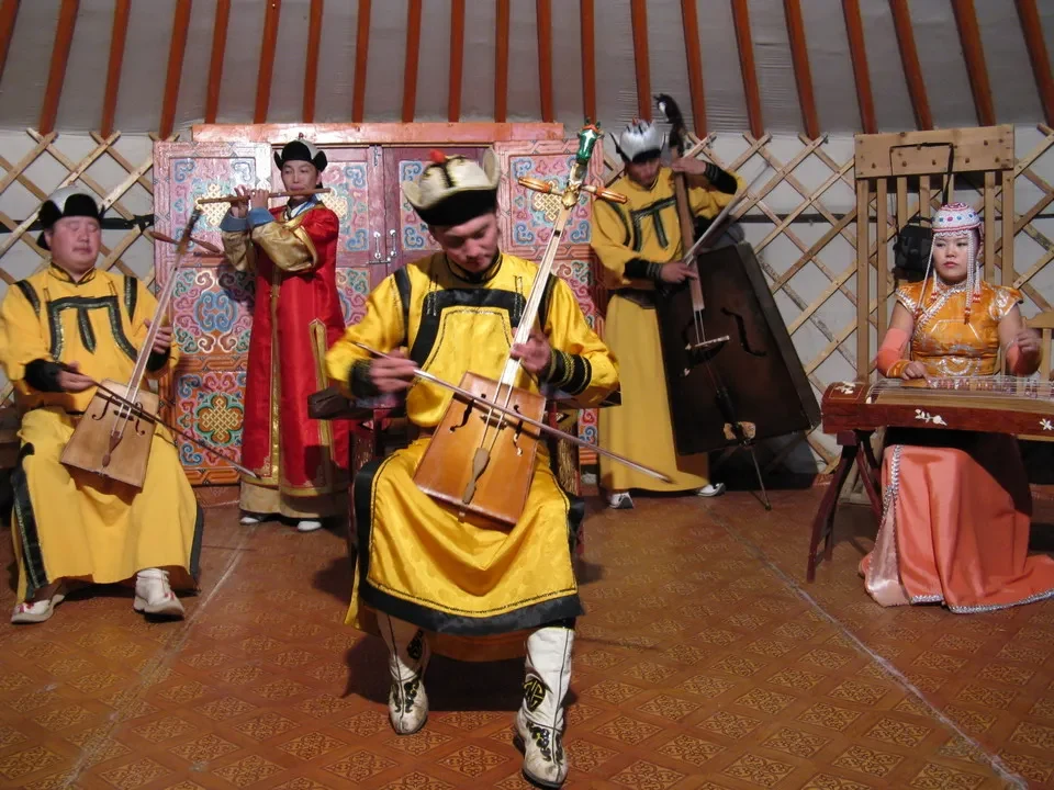 Danza tradizionale mongola con musicisti in costumi colorati.