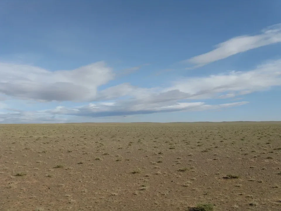 Vasto paesaggio di steppa sotto un cielo parzialmente nuvoloso.